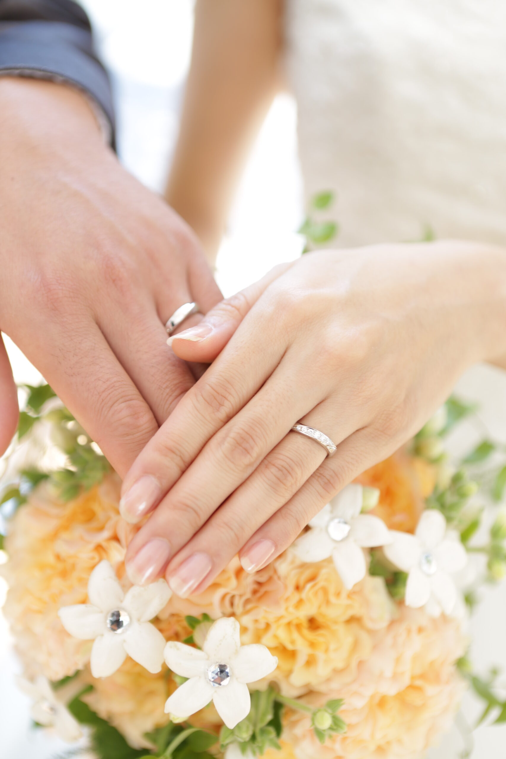 ブーケの上に重ねた新郎新婦の手。結婚指輪No3のペアリングを着けて